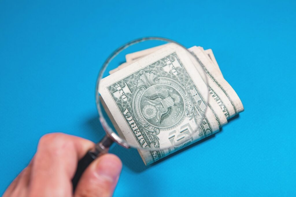 Magnifying glass over folded US dollar bills, representing scrutiny of processor fee quotes