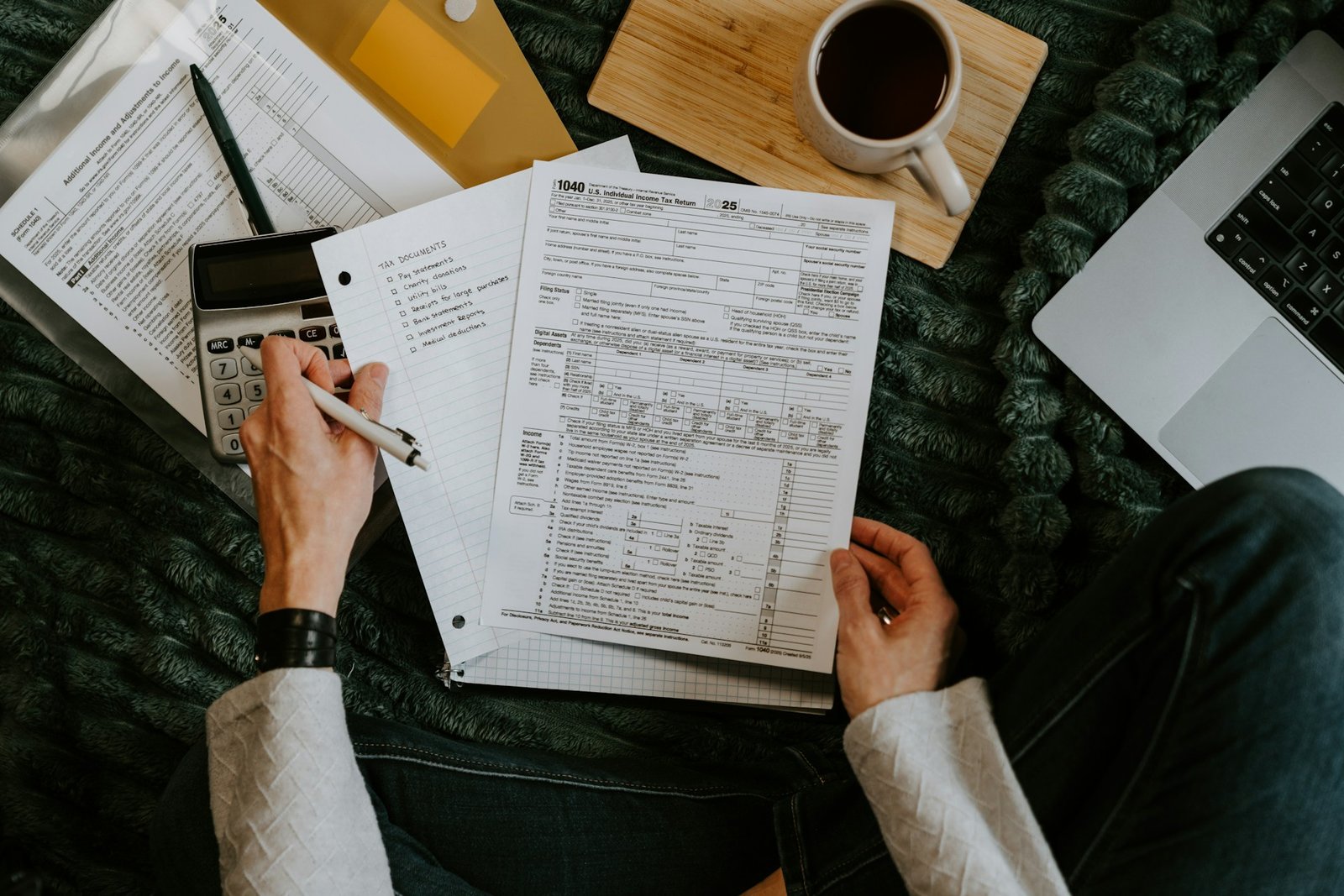 Person reviewing documents with a calculator and laptop for tax time