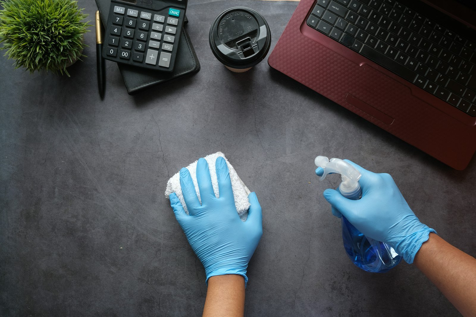 Gloved hands wiping down a desk to illustrate how to clean up a messy QuickBooks file