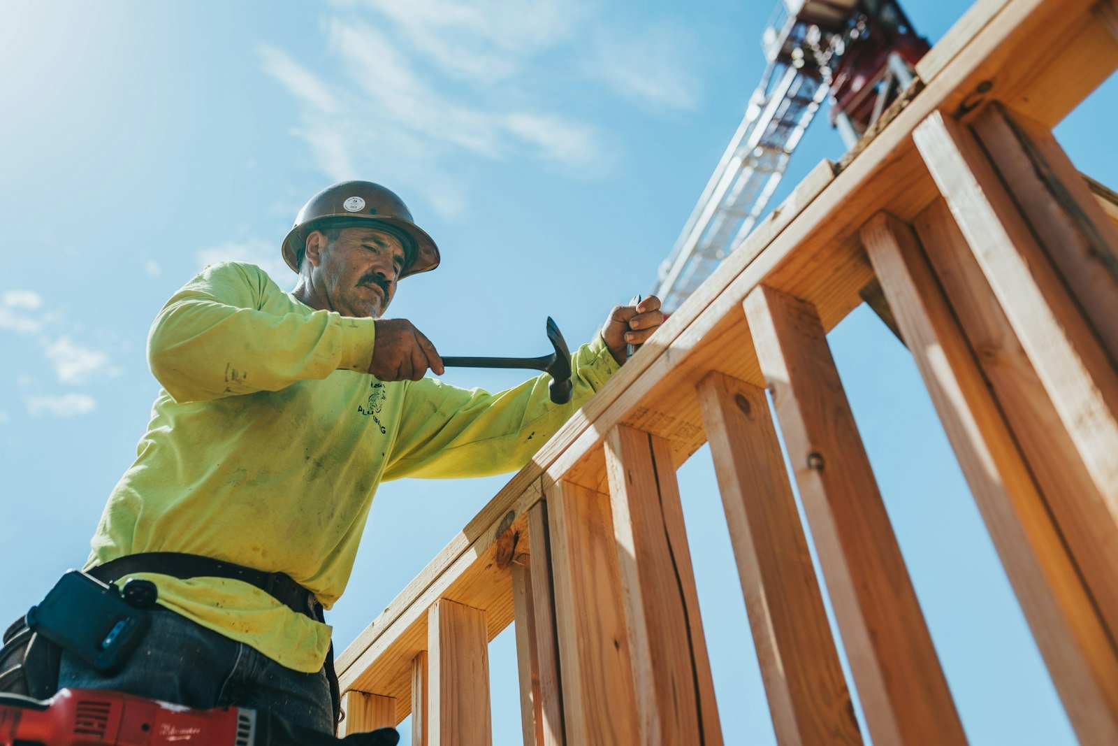 Contractor wearing a hard hat and safety gear working on a wooden structure