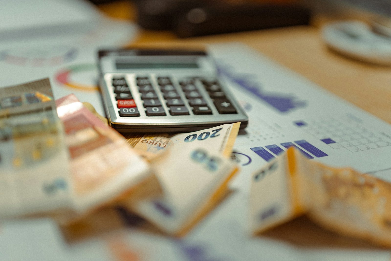 Calculator on a pile of money, comparing QuickBooks Online vs Desktop costs over five years