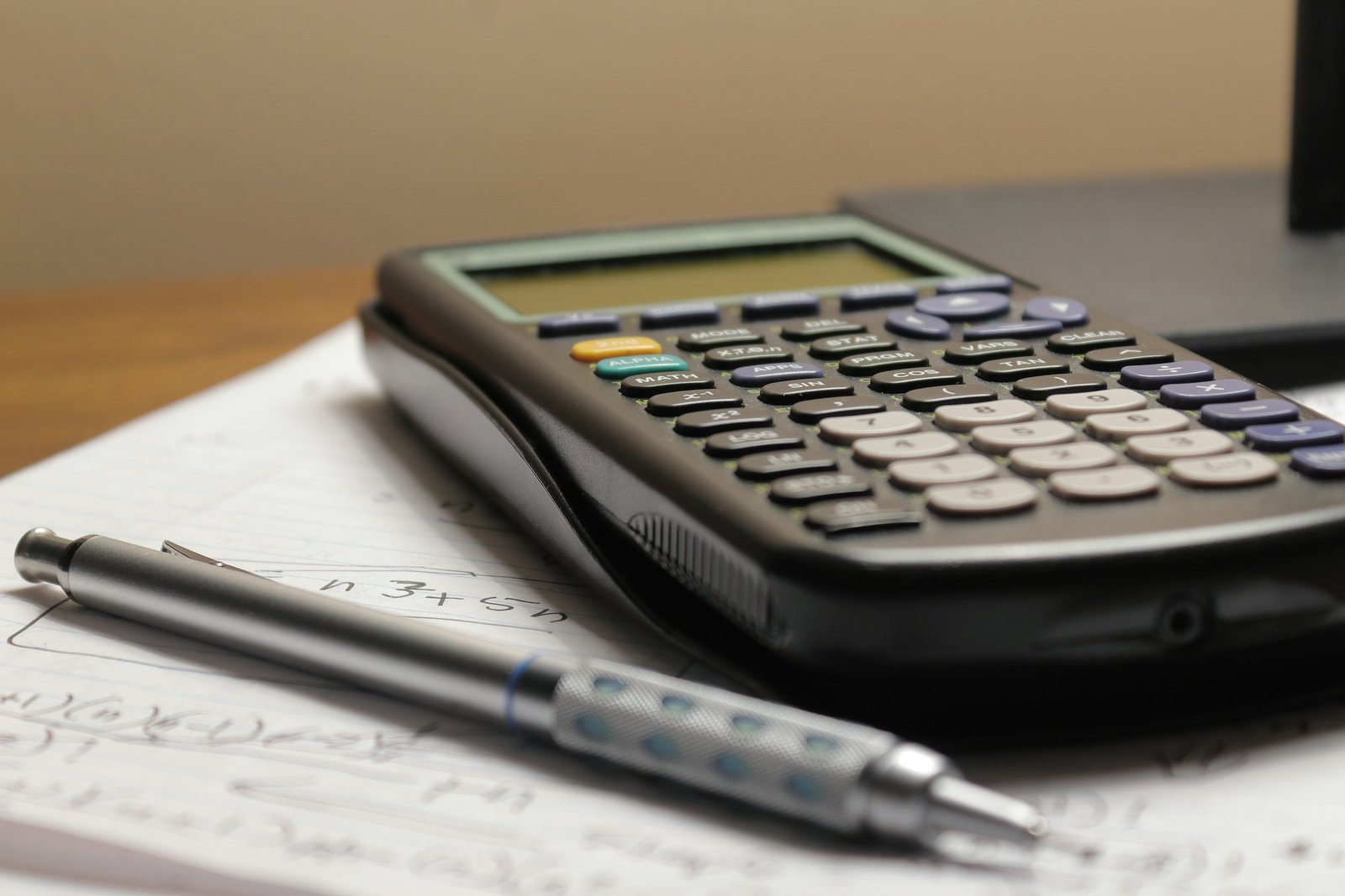 A calculator and a pen on top of a piece of paper