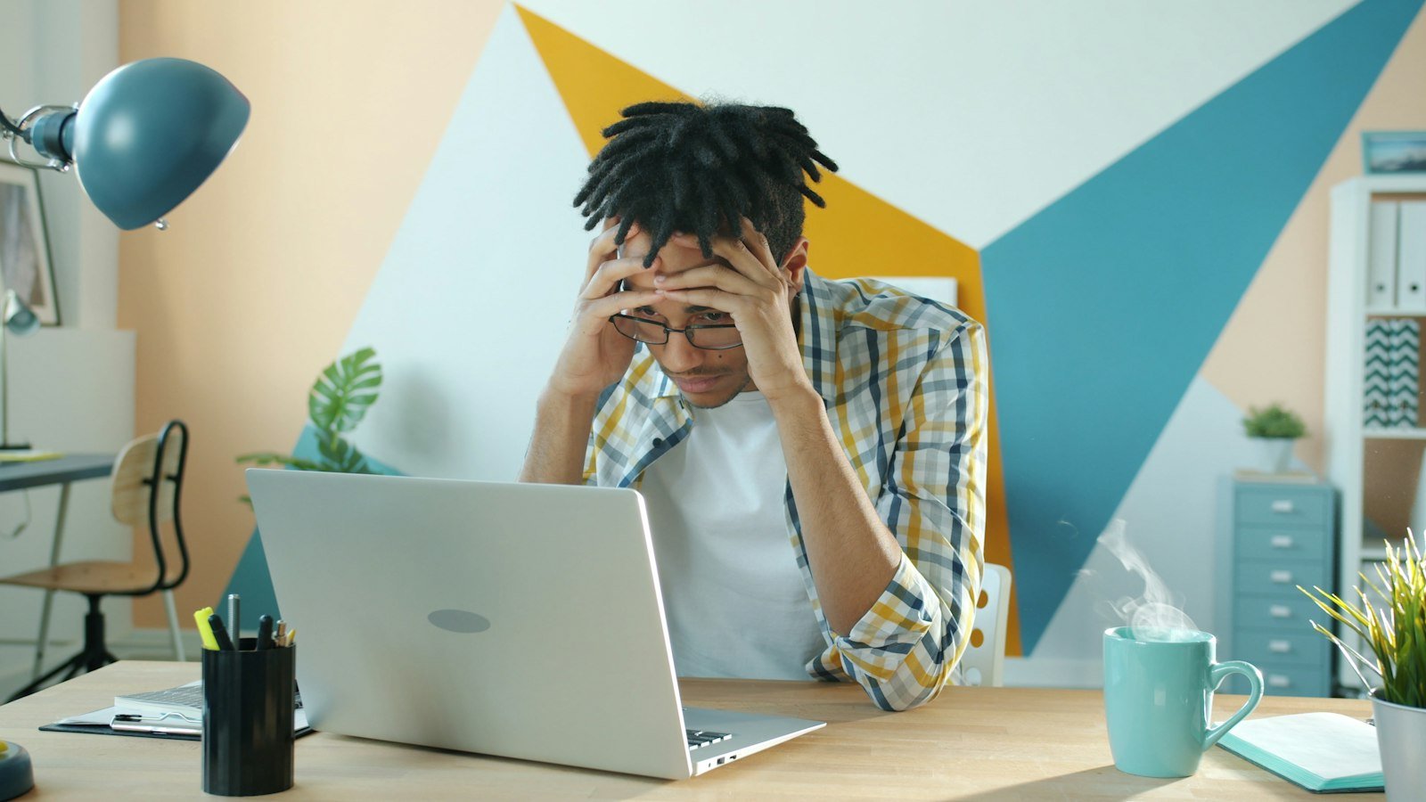 Frustrated person holding their head at a desk while QuickBooks running slow wastes their time