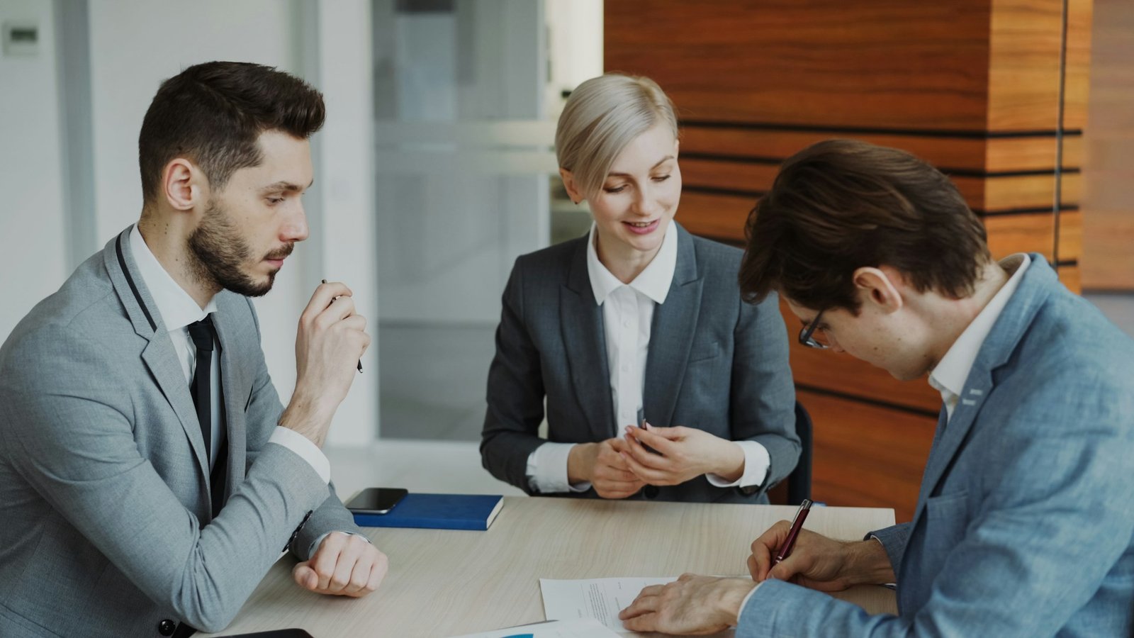 Business people signing a contract at a table, representing law firm trust accounting needs