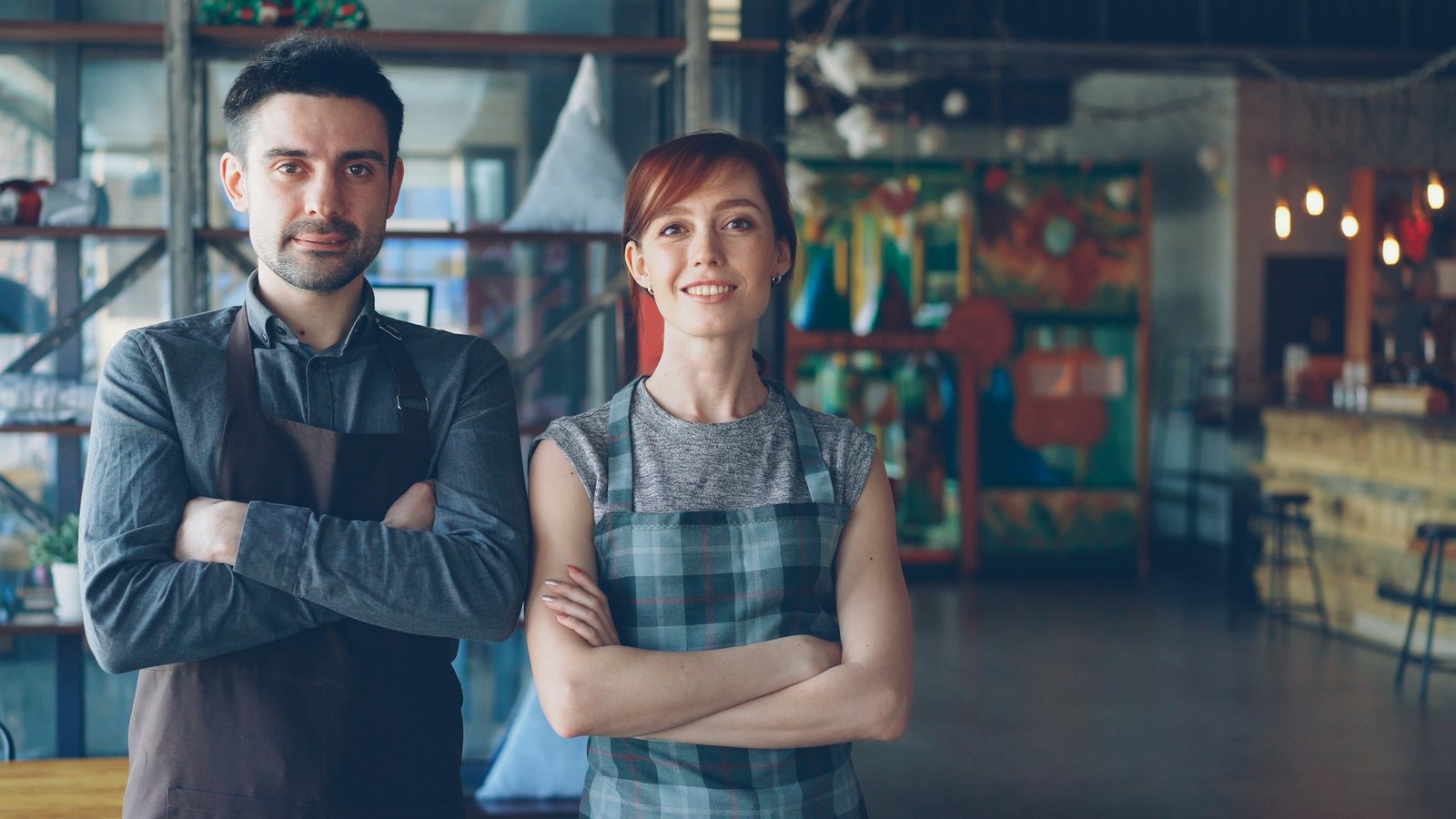 Confident restaurant owners posing with arms crossed