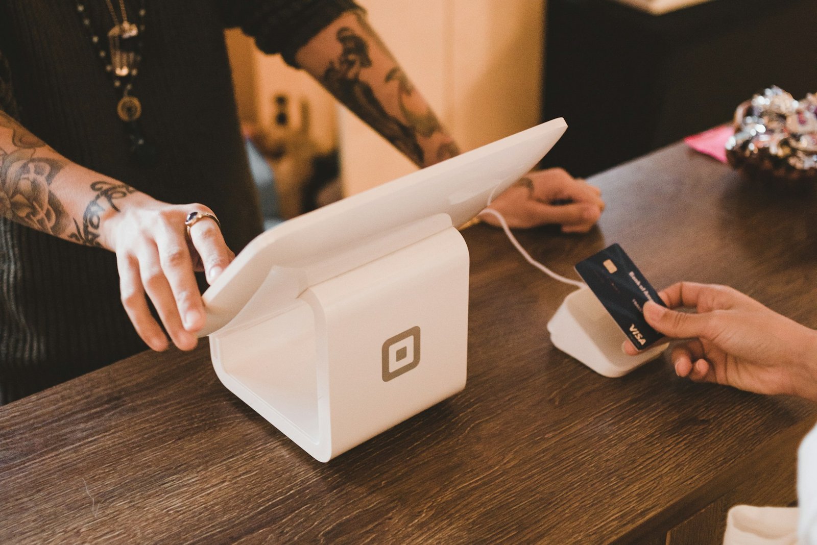Person holding a white payment terminal to process a card transaction