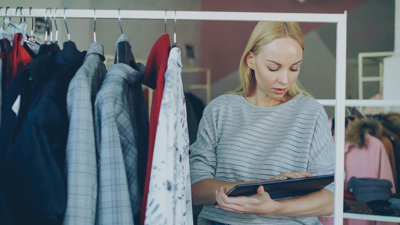 Store employee checking inventory on the shelves of a clothing shop