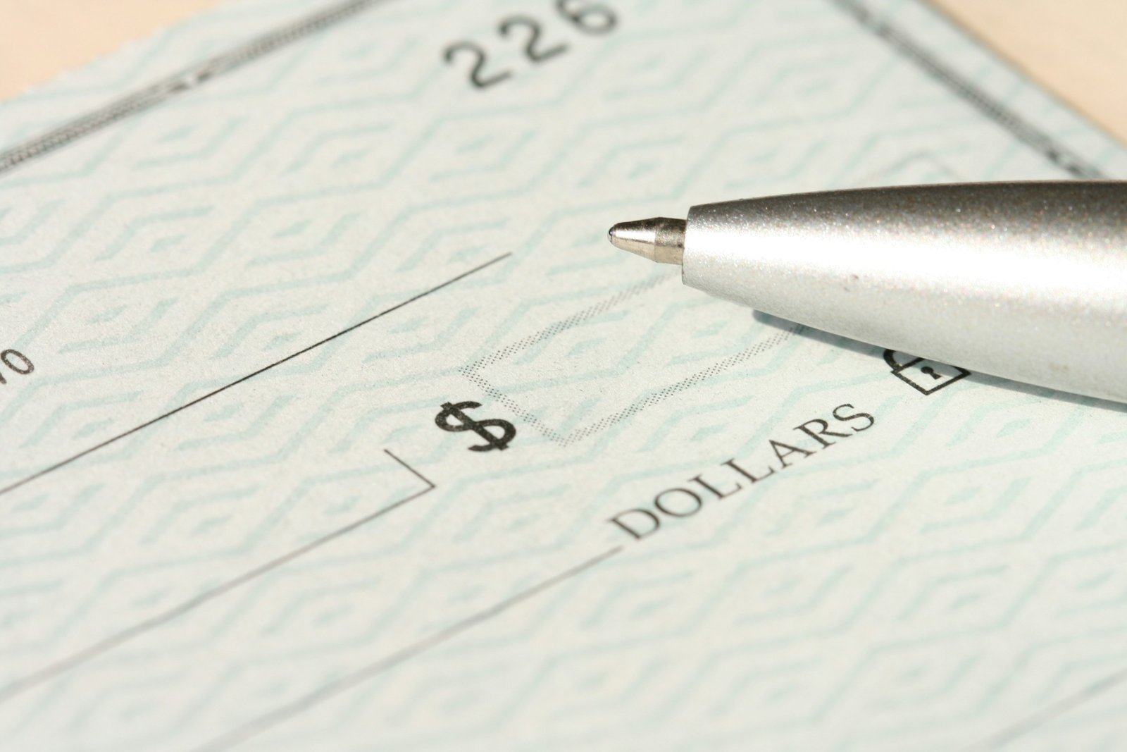 A pen resting on a check near the money line