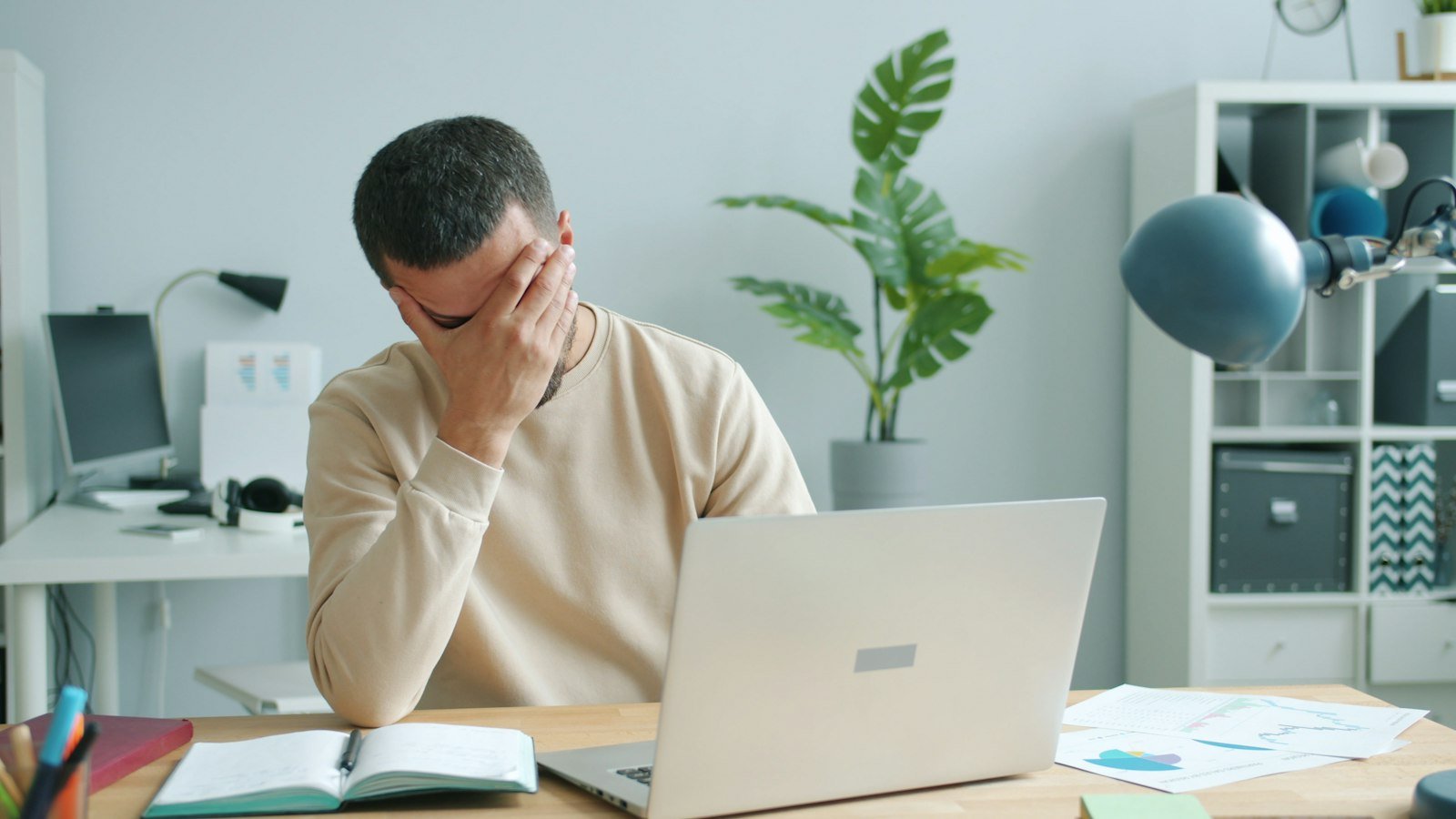 Man rubbing his face in frustration in front of a laptop that will not open QuickBooks