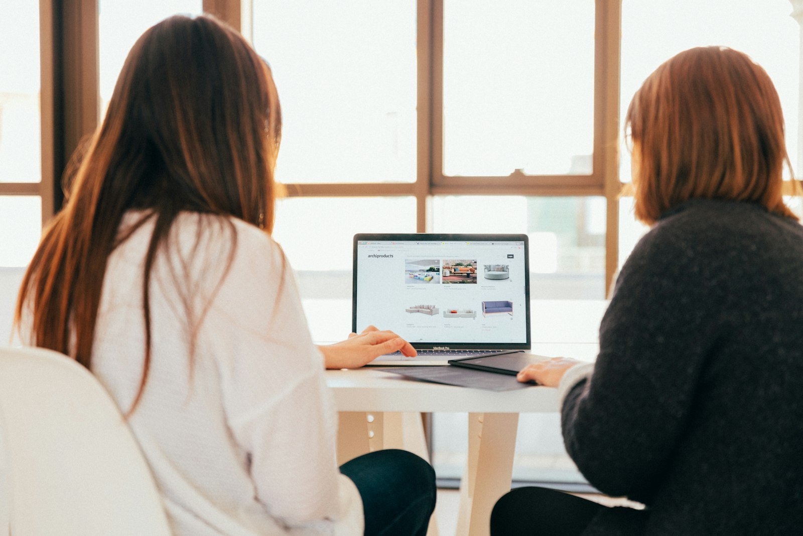 Two women talking while looking at a laptop together