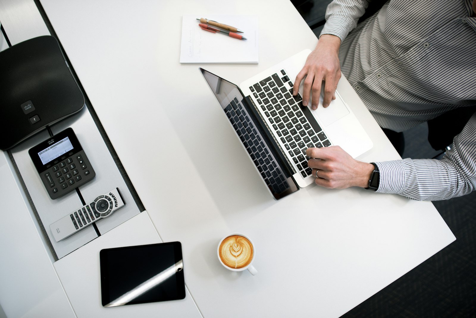 Person using a laptop at a white wooden table