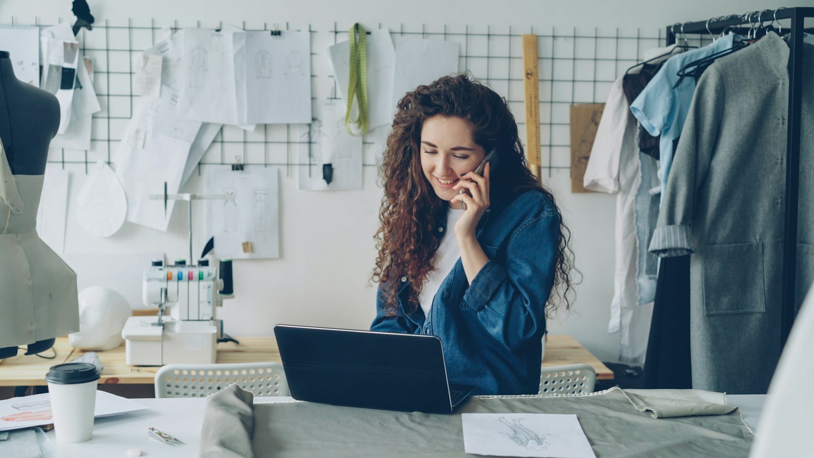 Small business owner on the phone while working on a laptop surrounded by product