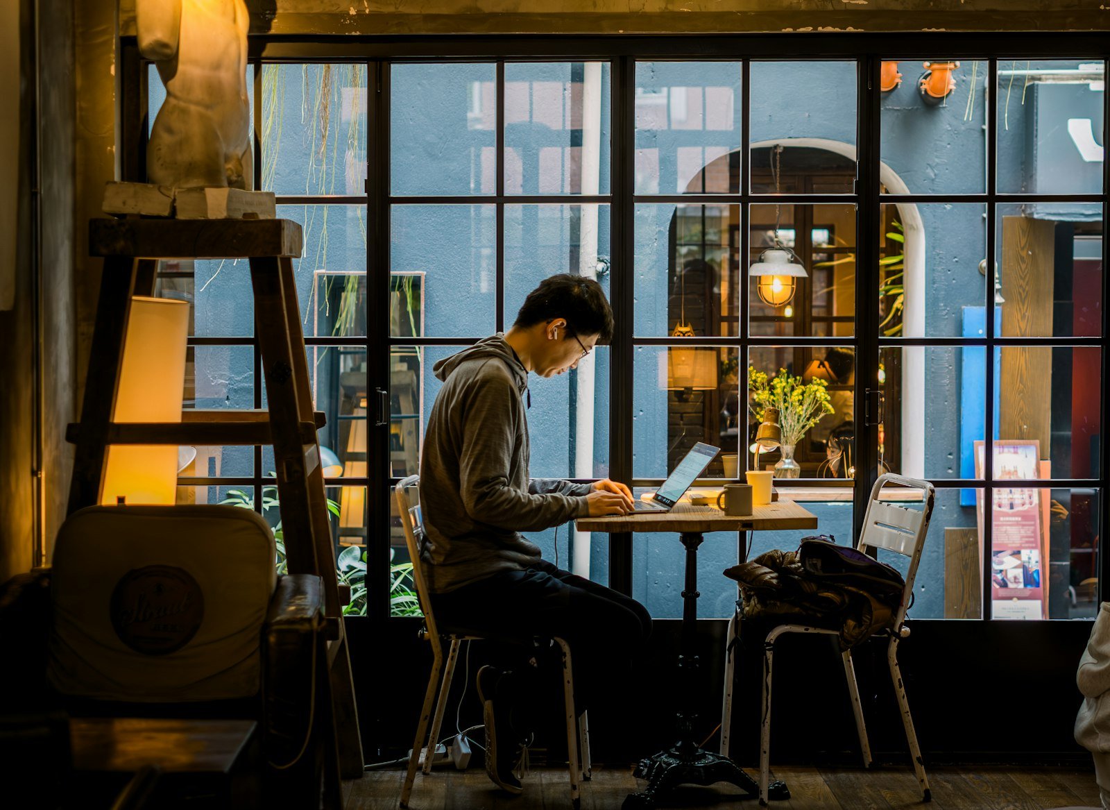 Man working on a laptop in a cafe next to the window
