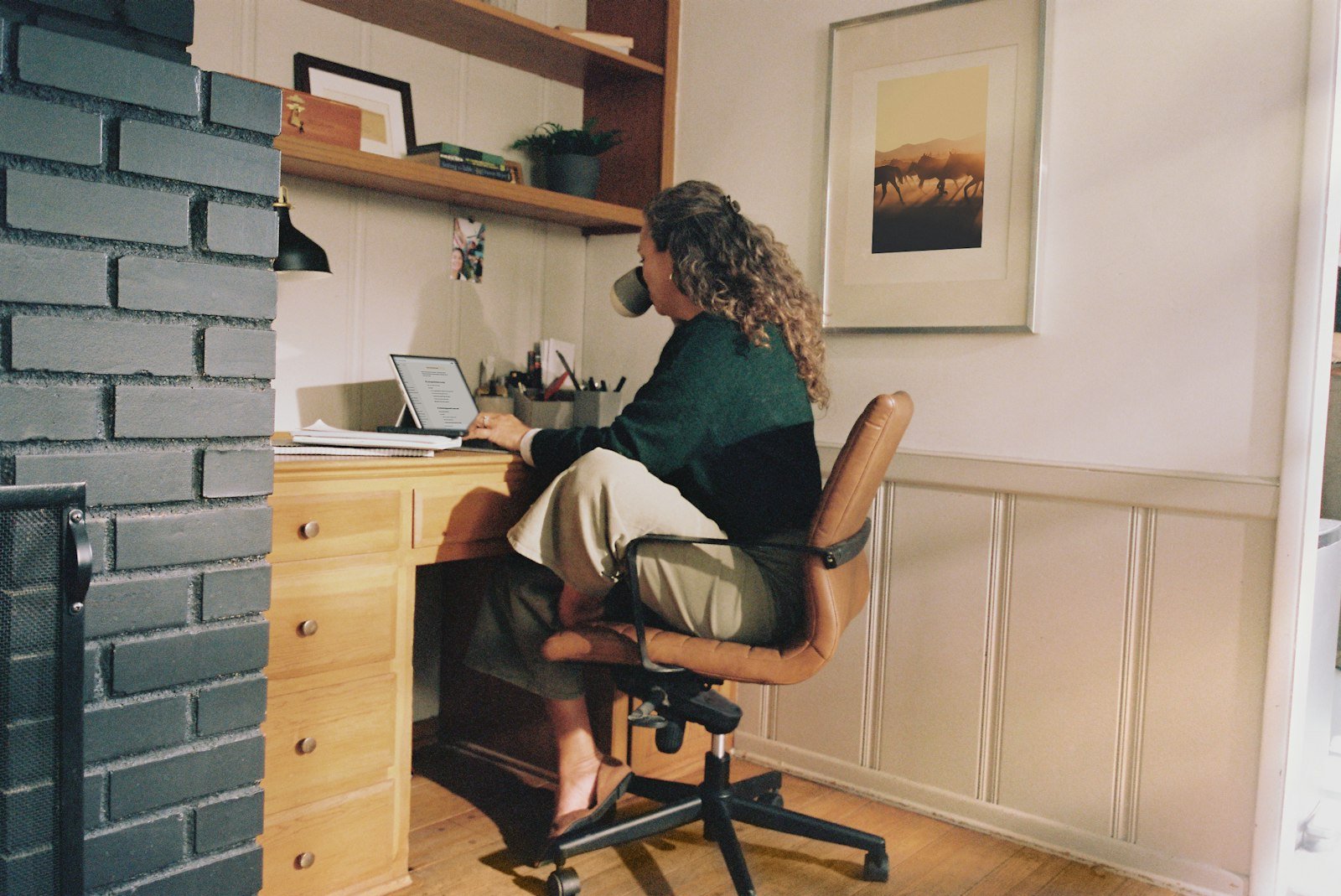 Woman working at a home office desk with a cup of coffee