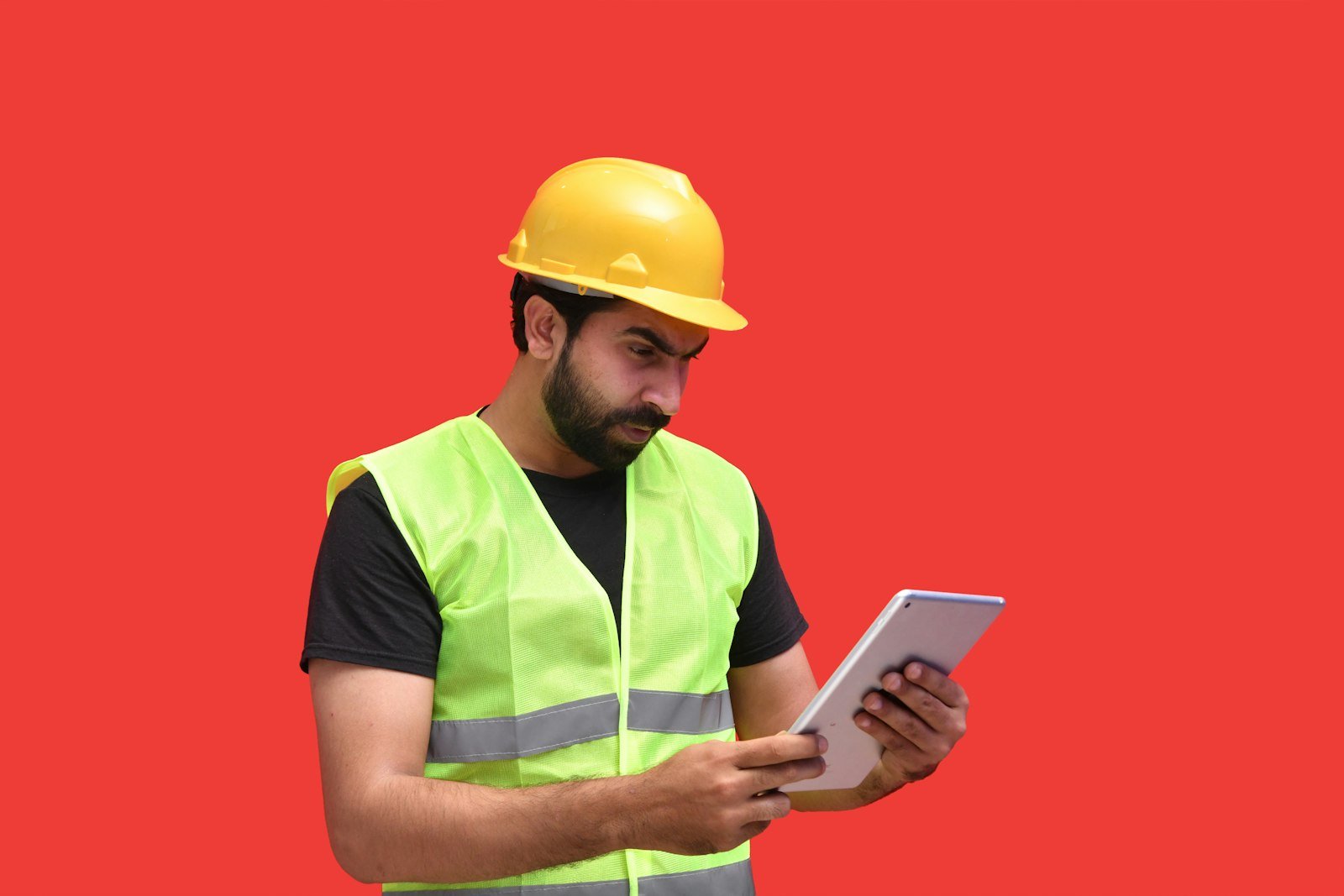 Man wearing a yellow hard hat holding a tablet on a construction site
